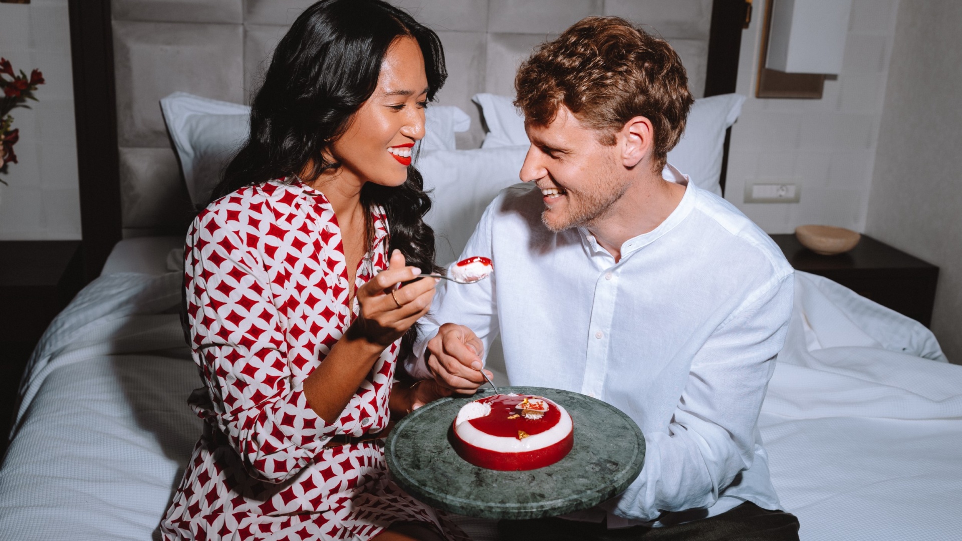Elegant couple sharing a Valentine’s Day dessert in bed at Electra Hotels in Athens the perfect setting for romantic getaways for couples.