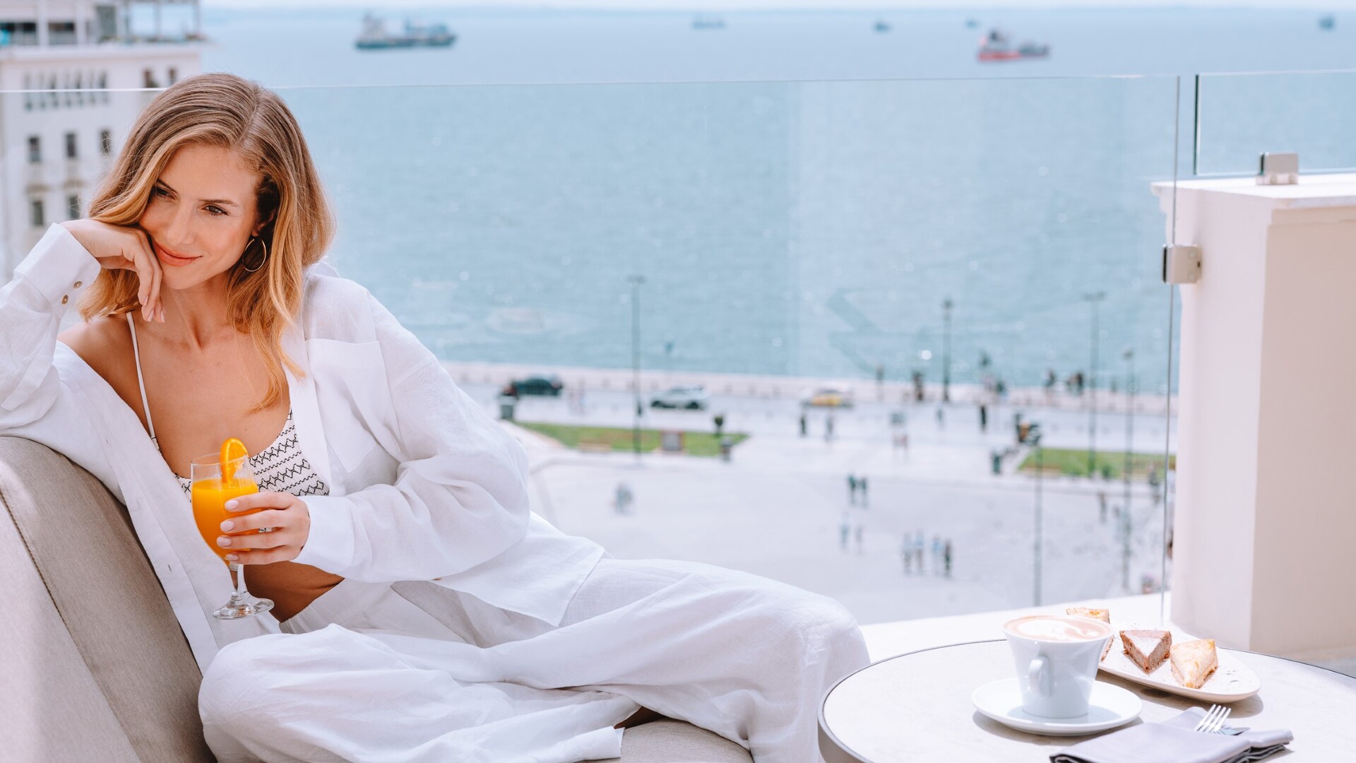 Female guest enjoying the ambiance of spring in Thessaloniki on a seaview balcony at Electra Palace on Aristotelous Square.
