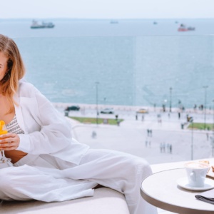 Female guest enjoying the ambiance of spring in Thessaloniki on a seaview balcony at Electra Palace on Aristotelous Square.