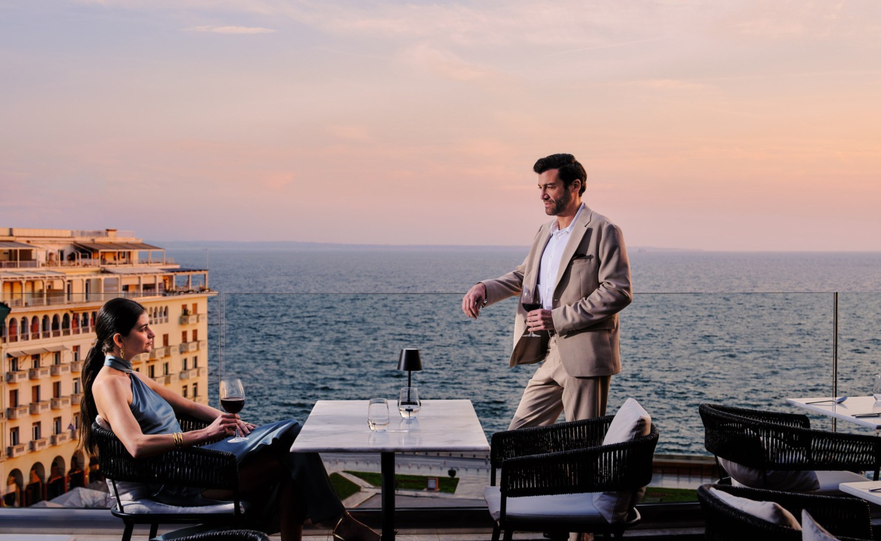 A couple enjoying wine at Orizontes Roof Garden overlooking Aristotelous Square and the Thermaic Gulf, an ideal for foodie travel in Thessaloniki.