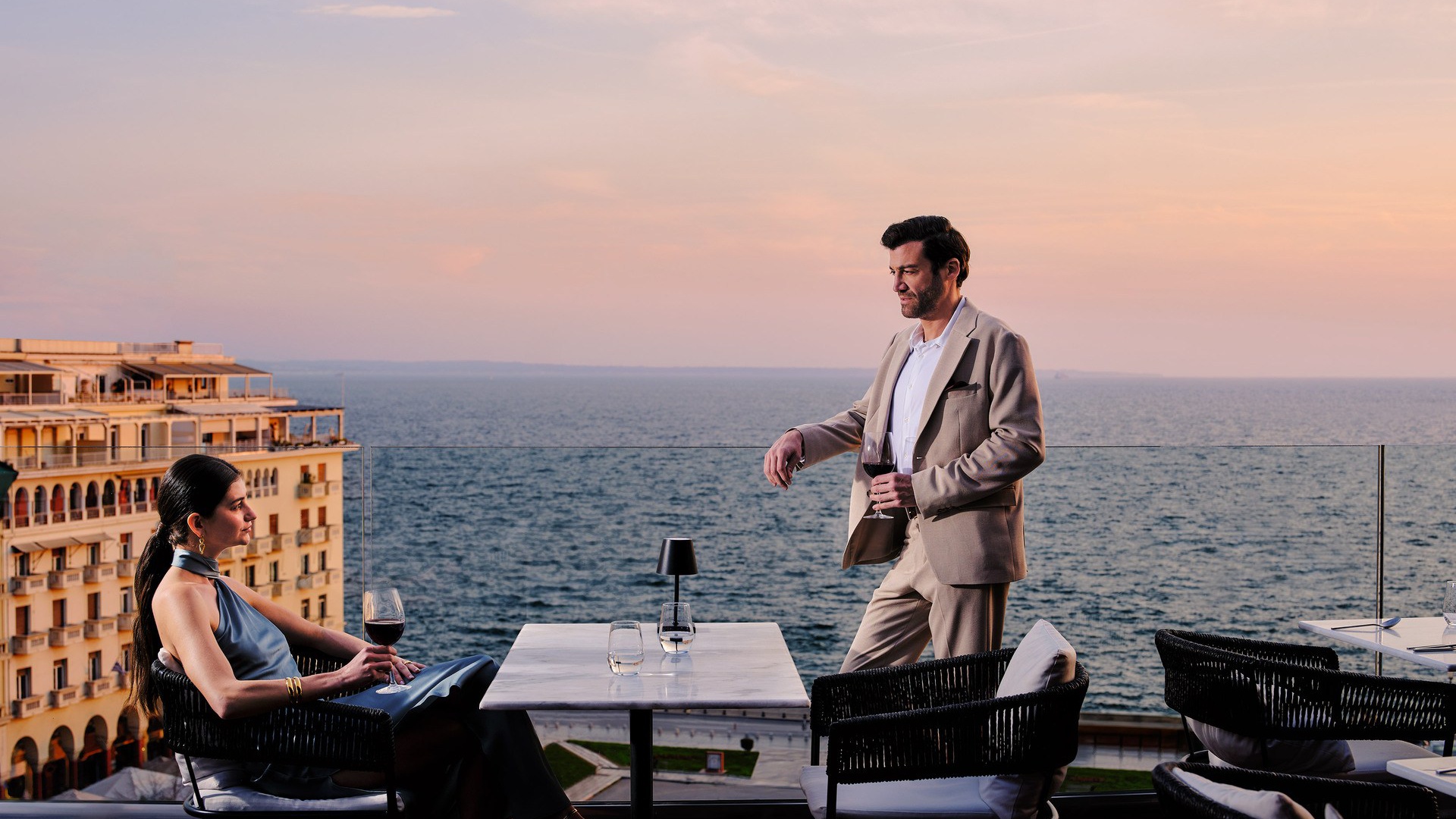 A couple enjoying wine at Orizontes Roof Garden overlooking Aristotelous Square and the Thermaic Gulf, an ideal for foodie travel in Thessaloniki.